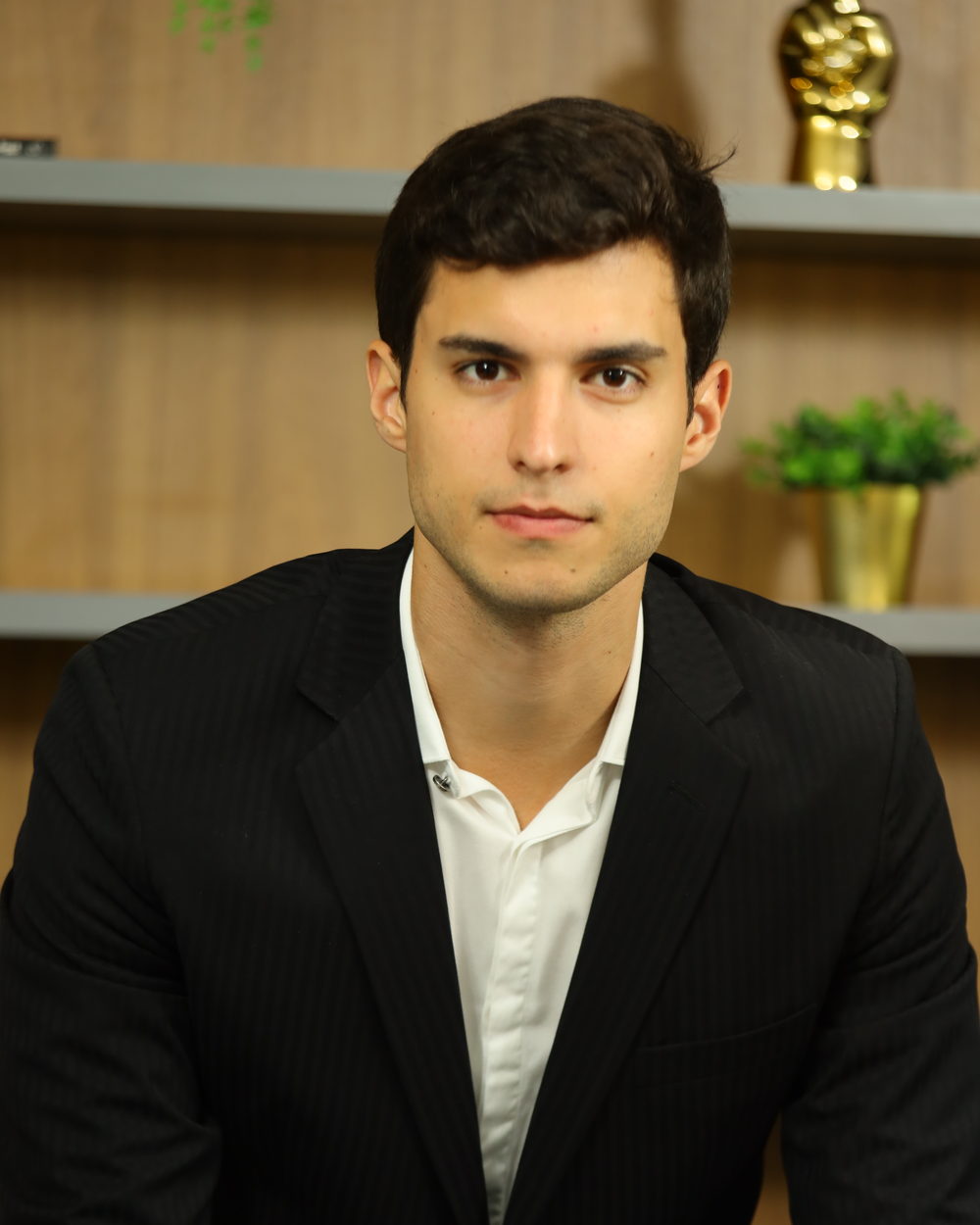 Filipe Machado, assessor de investimentos, de terno escuro em seu escritório
